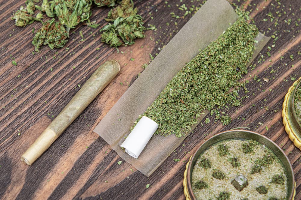 An unrolled joint filled with cannabis flower lays on a wooden table at Options Cannabis Company